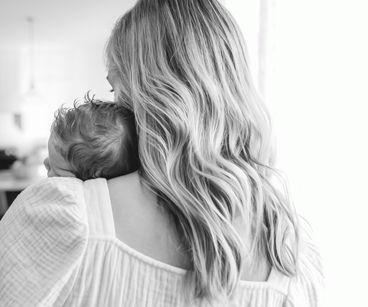 back of mom with newborn baby head on her shoulder