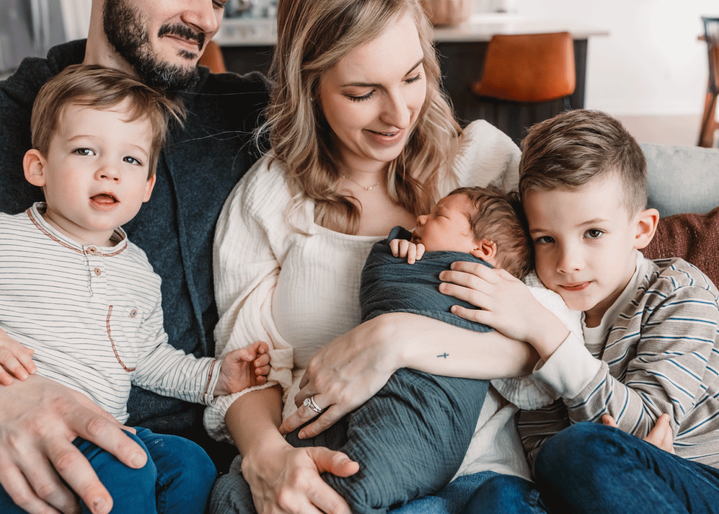 family on couch snuggling with newborn baby