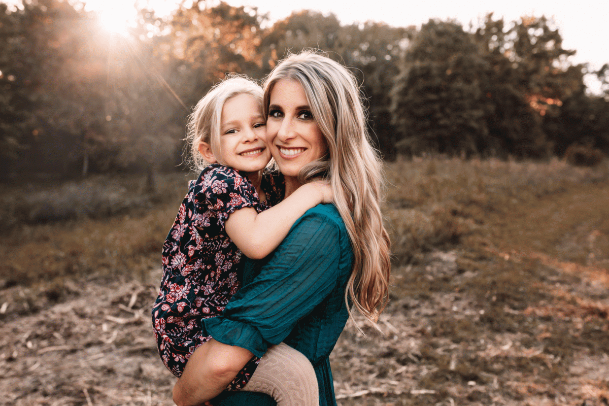 mom holding little girl with sunset