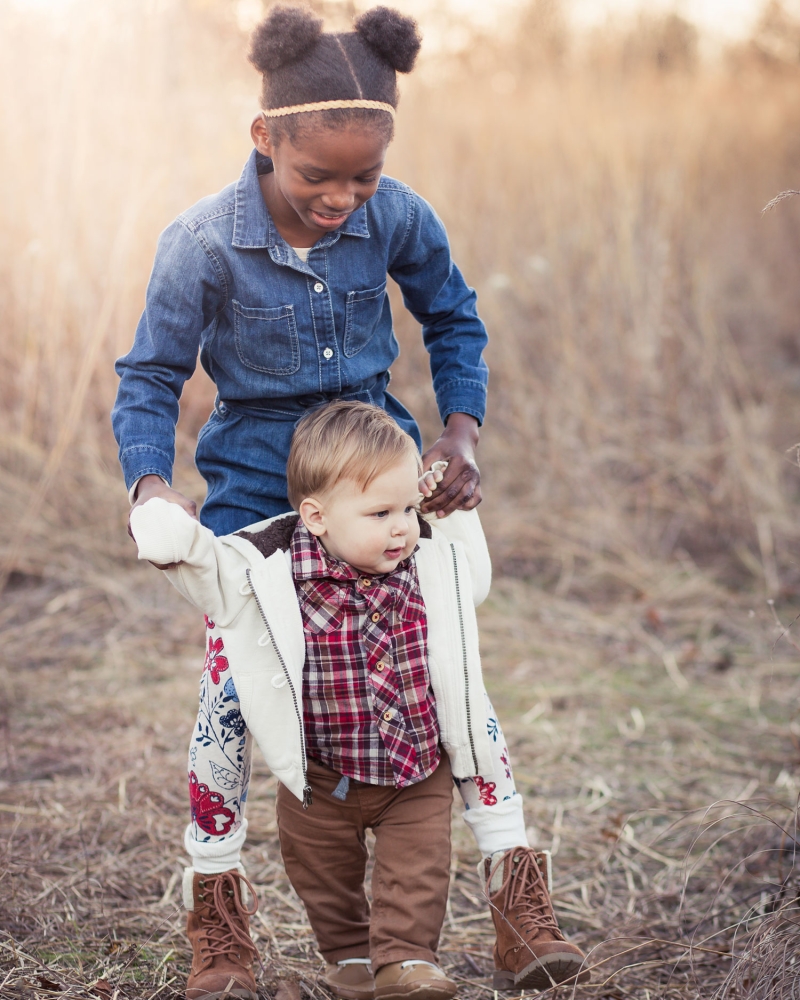 older sister helping little brother walk